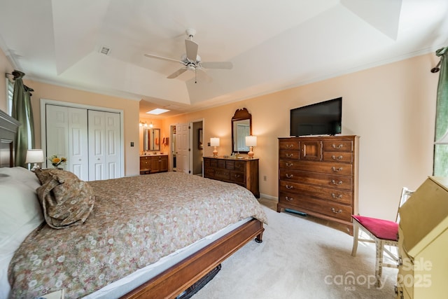 bedroom with carpet flooring, a closet, a tray ceiling, crown molding, and ensuite bathroom