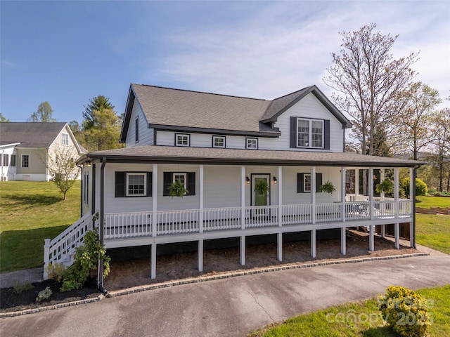 farmhouse inspired home featuring a front lawn, a shingled roof, and covered porch