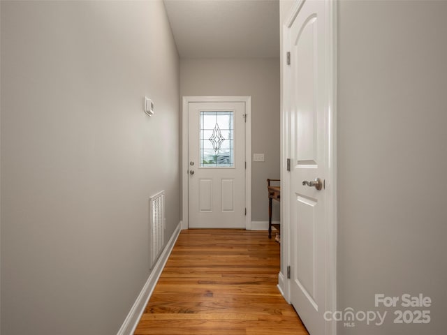 doorway with visible vents, baseboards, and light wood finished floors