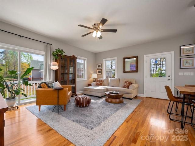 living room featuring light wood-style floors, baseboards, and ceiling fan