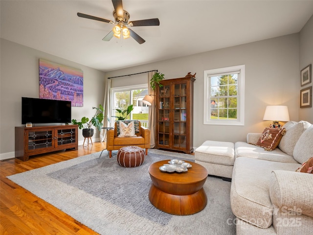 living room featuring ceiling fan, baseboards, and wood finished floors