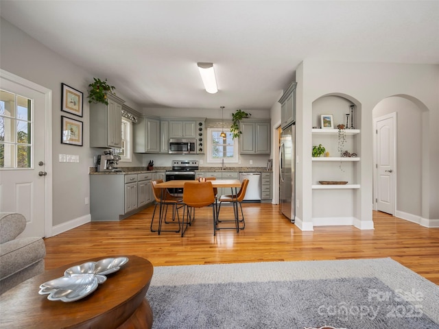 kitchen featuring light wood-type flooring, gray cabinetry, open shelves, and stainless steel appliances