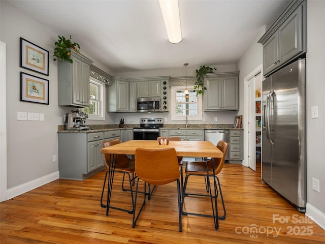 kitchen featuring gray cabinetry, light wood-style flooring, baseboards, and appliances with stainless steel finishes