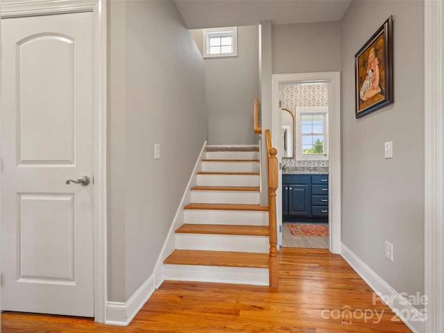 staircase with wood finished floors, baseboards, and a wealth of natural light