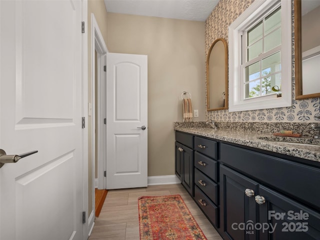 bathroom with a sink, baseboards, and double vanity