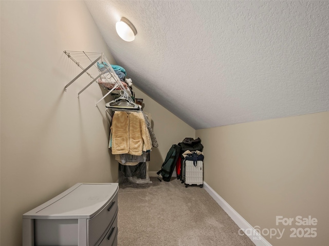 walk in closet featuring light carpet and vaulted ceiling