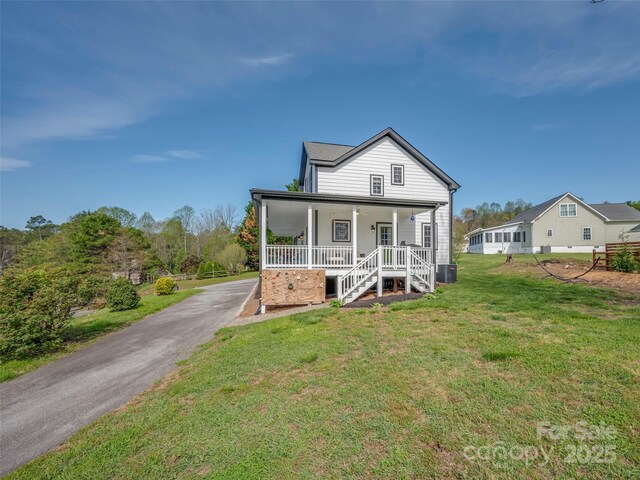 view of front of property with a front yard, central AC unit, driveway, and covered porch