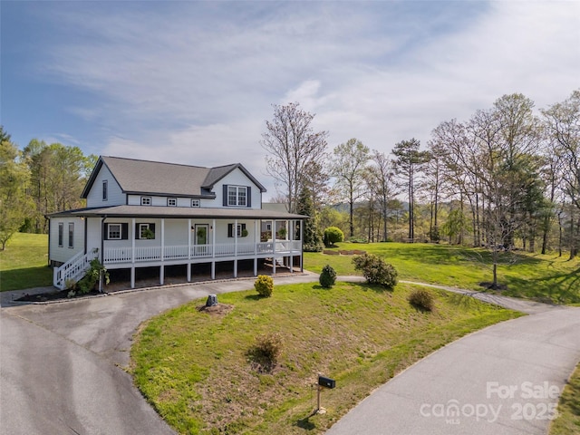farmhouse inspired home with covered porch, driveway, and a front lawn