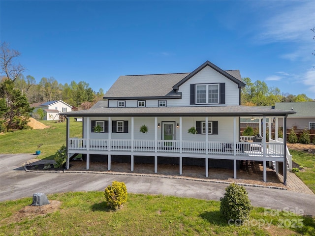 farmhouse featuring covered porch, a front yard, and roof with shingles