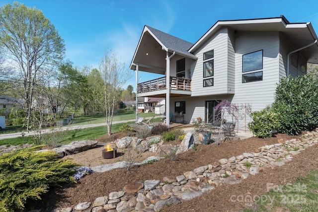 rear view of house with a fire pit, a balcony, and a patio