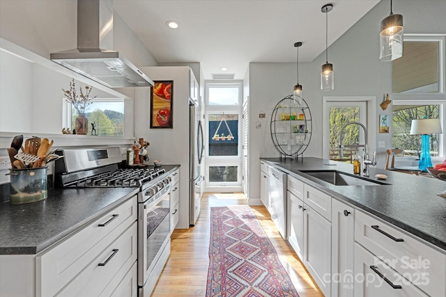 kitchen featuring stainless steel appliances, dark countertops, a healthy amount of sunlight, island range hood, and a sink