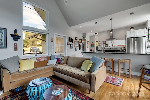 living room with recessed lighting, light wood-type flooring, and high vaulted ceiling