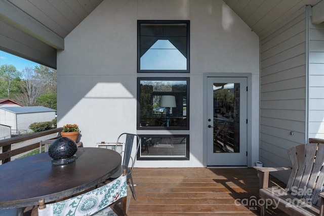 view of exterior entry with stucco siding and a deck