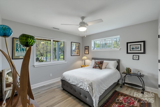 bedroom with light wood-style floors, visible vents, a ceiling fan, and baseboards