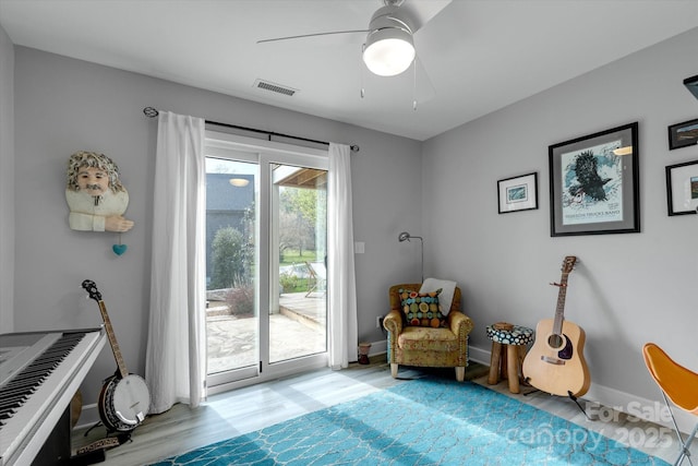 sitting room with light wood-type flooring, baseboards, ceiling fan, and visible vents