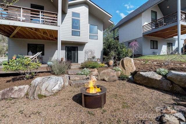 rear view of house with an outdoor fire pit and a balcony