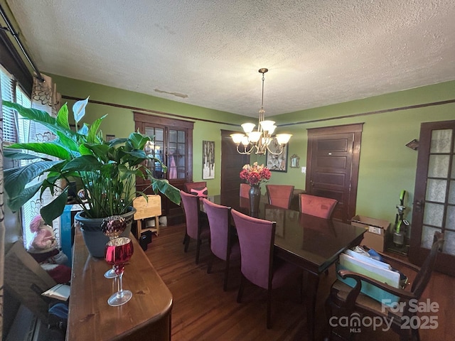 dining area with a chandelier, a textured ceiling, and wood finished floors