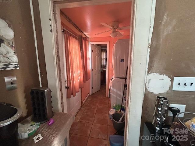 corridor with stacked washer and clothes dryer and tile patterned flooring
