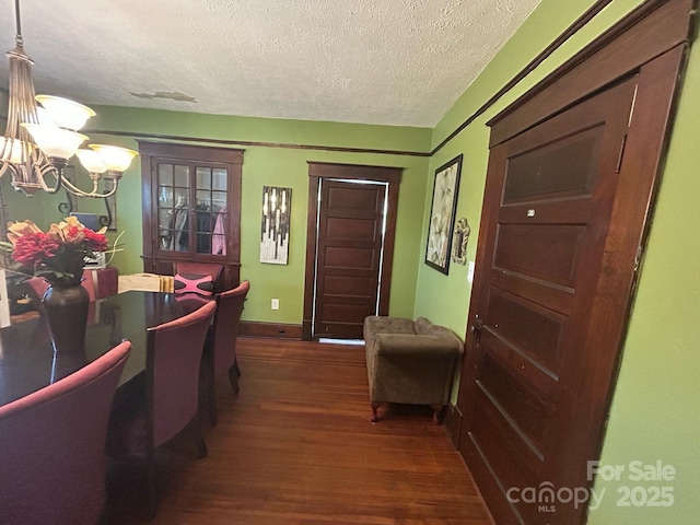 interior space with baseboards, dark wood-style floors, a notable chandelier, and a textured ceiling