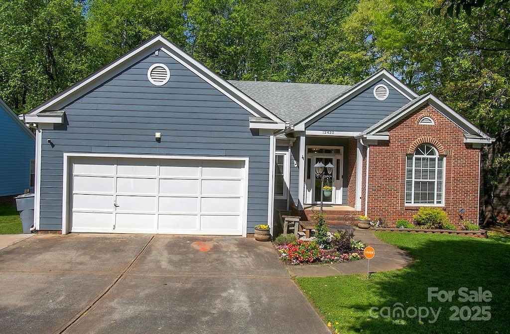 ranch-style home with concrete driveway, an attached garage, brick siding, and a front yard