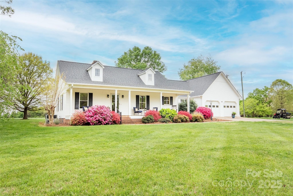 new england style home featuring roof with shingles, an attached garage, a front lawn, a porch, and driveway