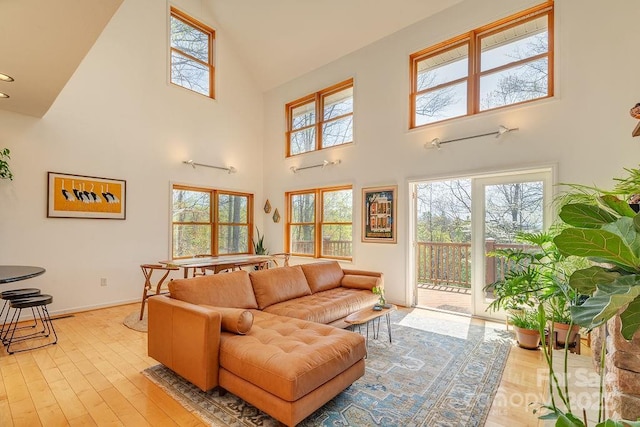 living room with baseboards, light wood finished floors, and high vaulted ceiling