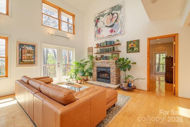 living room featuring light wood-style floors, a high ceiling, baseboards, and a healthy amount of sunlight