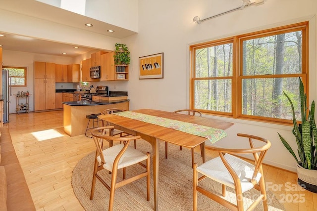 dining room with light wood finished floors, baseboards, and recessed lighting