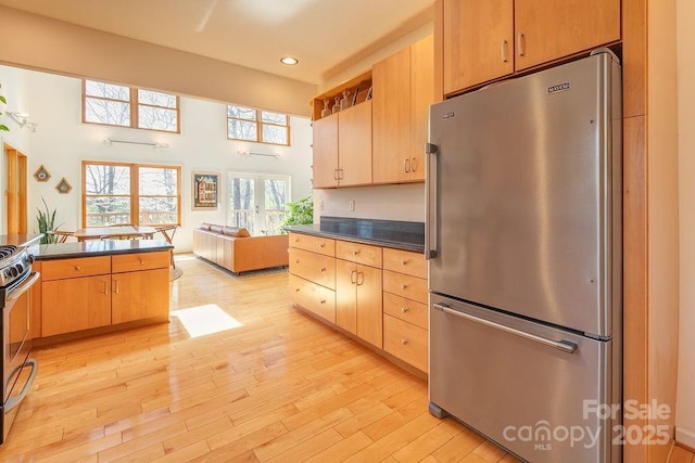 kitchen with dark countertops, open floor plan, light wood-style flooring, appliances with stainless steel finishes, and recessed lighting