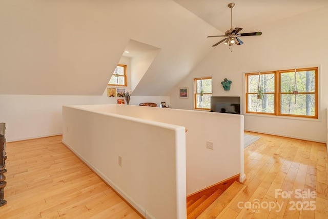 hall featuring vaulted ceiling, light wood-style floors, and baseboards