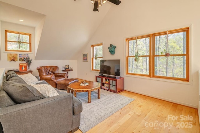 living area featuring lofted ceiling, light wood-style flooring, baseboards, and a ceiling fan