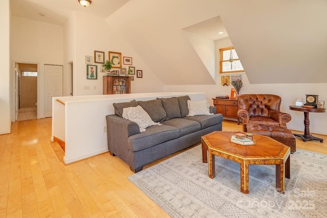living area featuring baseboards, lofted ceiling, and light wood-type flooring