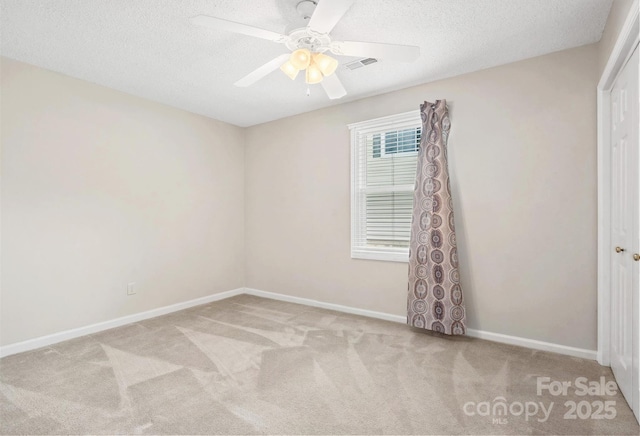 unfurnished room with carpet flooring, a textured ceiling, a ceiling fan, baseboards, and visible vents