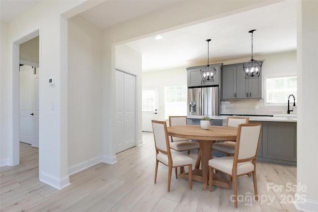 dining room with light wood-style flooring, a notable chandelier, baseboards, and recessed lighting