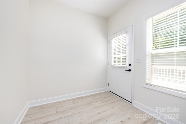 doorway with light wood finished floors and baseboards