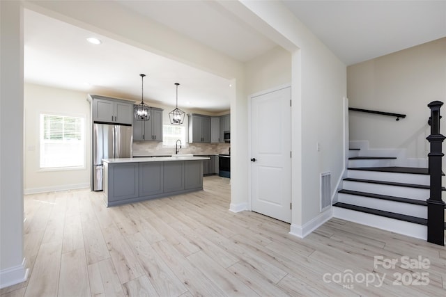 kitchen with a sink, stainless steel appliances, gray cabinets, visible vents, and light countertops