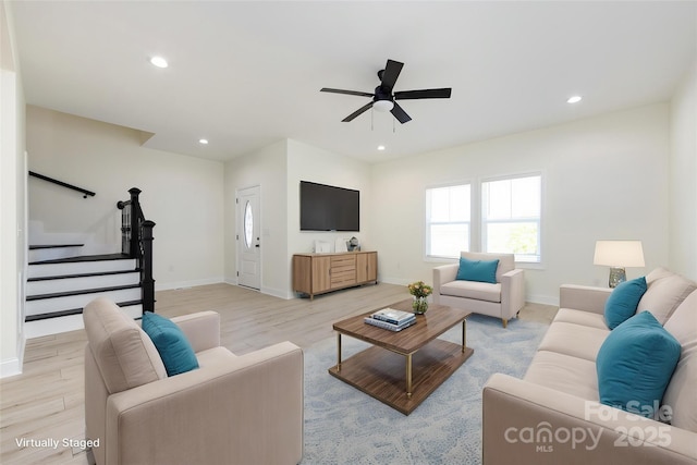 living room featuring baseboards, a ceiling fan, and light wood-style floors