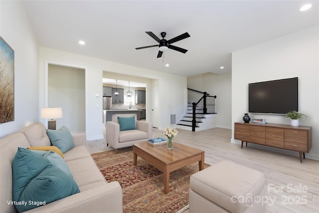 living area with light wood finished floors, stairs, a ceiling fan, and recessed lighting