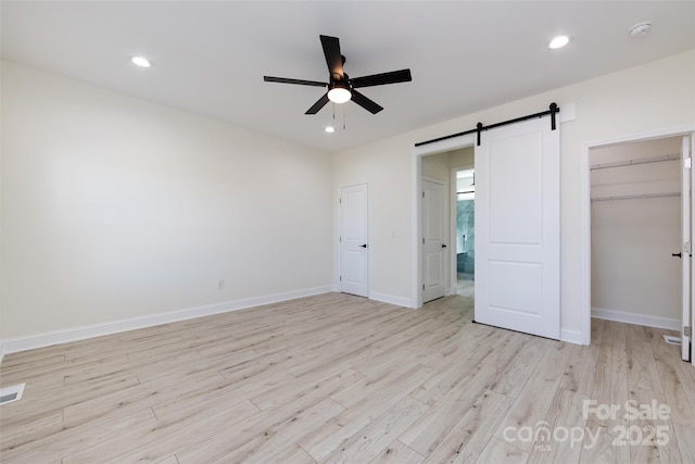 unfurnished bedroom featuring a barn door, visible vents, recessed lighting, light wood finished floors, and baseboards