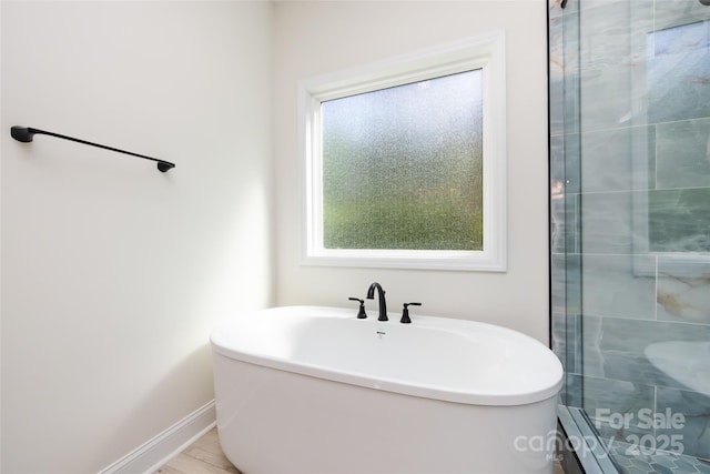 full bath featuring baseboard heating, baseboards, a stall shower, and a freestanding tub