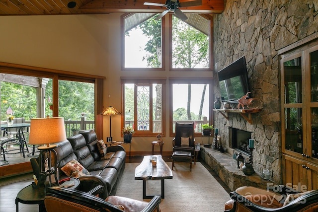 living area with a stone fireplace, ceiling fan, high vaulted ceiling, and wood ceiling