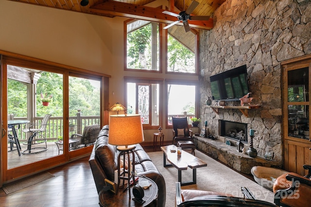 living room featuring wooden ceiling, wood-type flooring, a stone fireplace, and a wealth of natural light