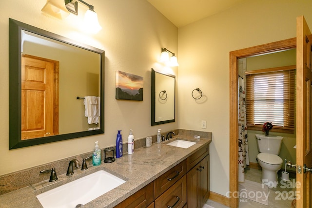 full bathroom with double vanity, baseboards, a sink, and toilet