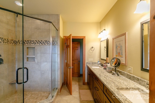 full bathroom with a sink, tile patterned floors, a shower stall, and double vanity