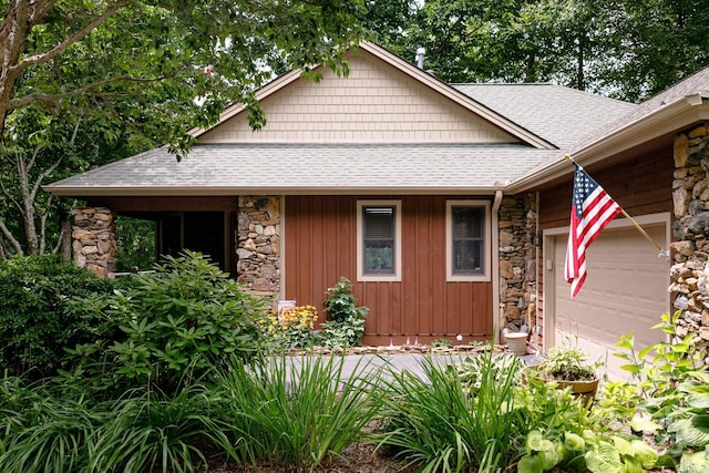 view of front of home with stone siding, an attached garage, and a shingled roof