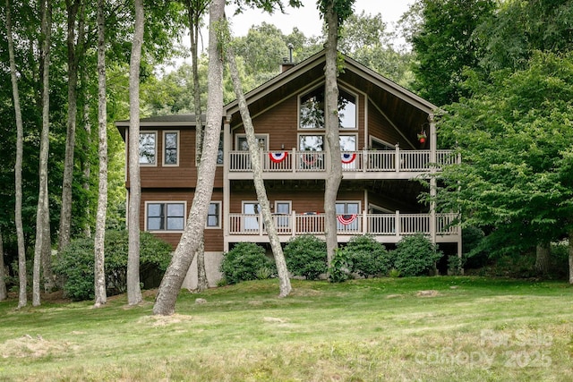 back of house with a balcony and a yard