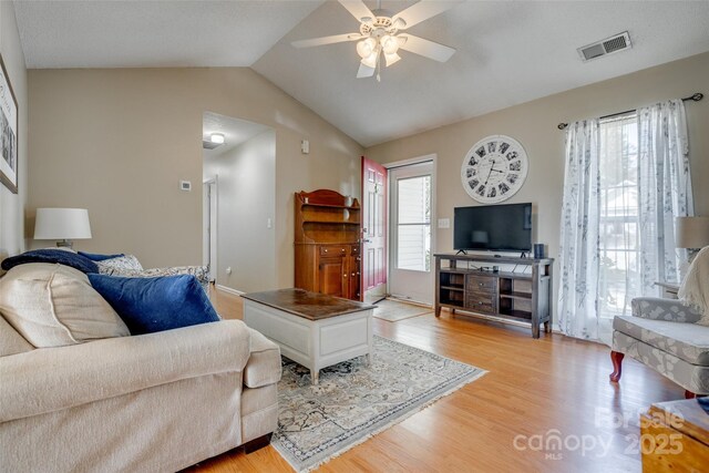 living area featuring a ceiling fan, visible vents, light wood-style floors, and vaulted ceiling