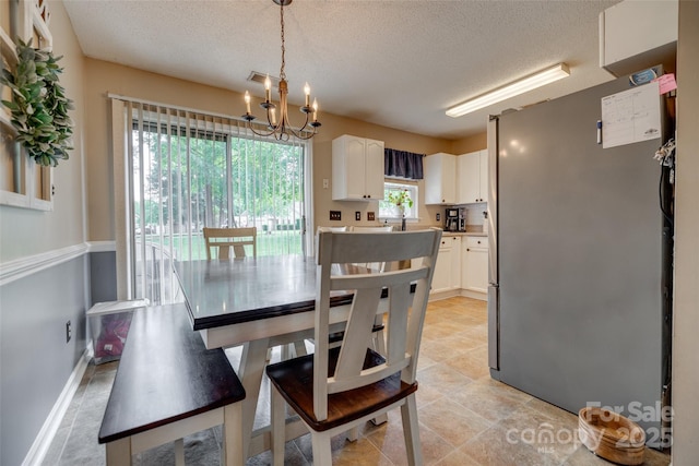 dining room with a textured ceiling, baseboards, a notable chandelier, and visible vents
