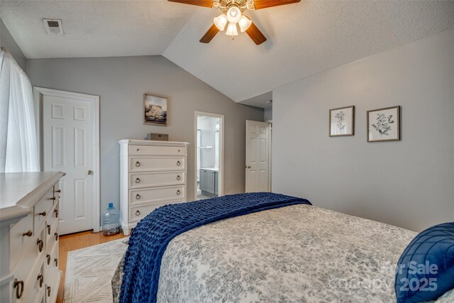 bedroom with light wood-style flooring, ensuite bathroom, visible vents, vaulted ceiling, and a ceiling fan