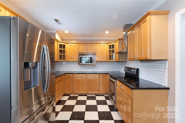 kitchen with appliances with stainless steel finishes, light floors, wall chimney range hood, glass insert cabinets, and recessed lighting